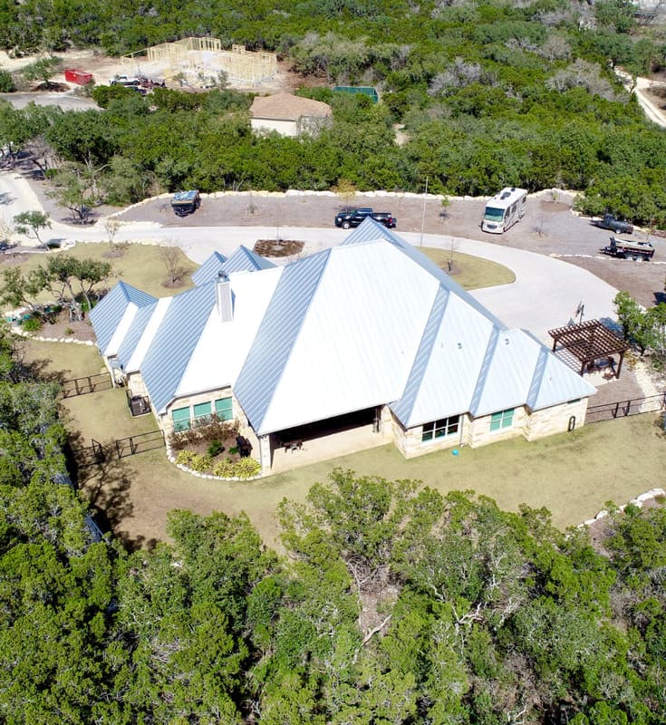 Standing-seam metal roof on a Hill Country stone home, installed by Apache Roofing & Construction